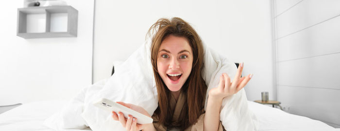 Portrait of young woman sitting on bed at home