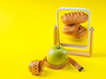 Close-up of apple on table against yellow background