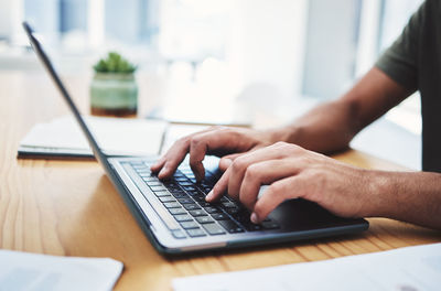 Midsection of man using laptop on table