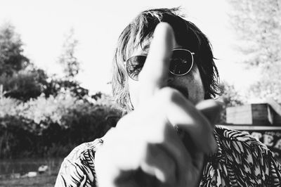 Close-up of mature man gesturing while standing against sky