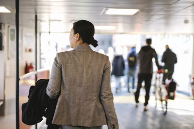 Rear view of businesswoman looking away while walking in ferry