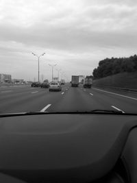 Cars on road against sky seen through car windshield