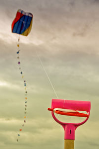 Low angle view of kite flying in cloudy sky at sunset