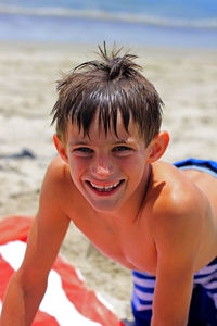 Close-up portrait of happy boy at beach on sunny day