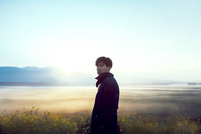 Rear view of woman standing against sea