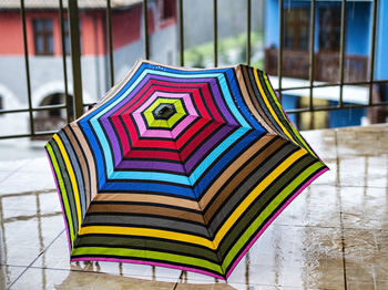 Multicolor umbrella close-up in drops of rain standing on the terrace , geometric rainbow pattern