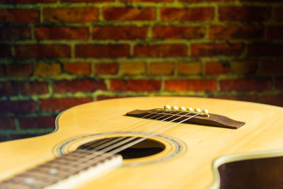 Close-up of guitar against brick wall