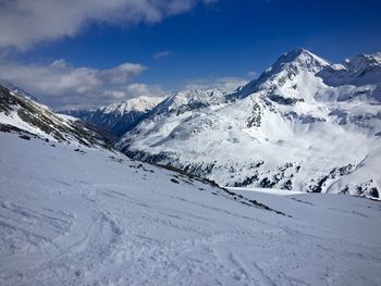 Scenic view of snow covered mountains against cloudy sky