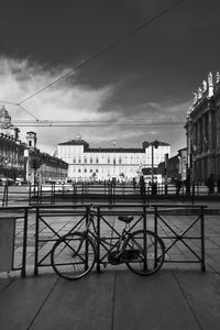 Bicycle on railing in city against sky