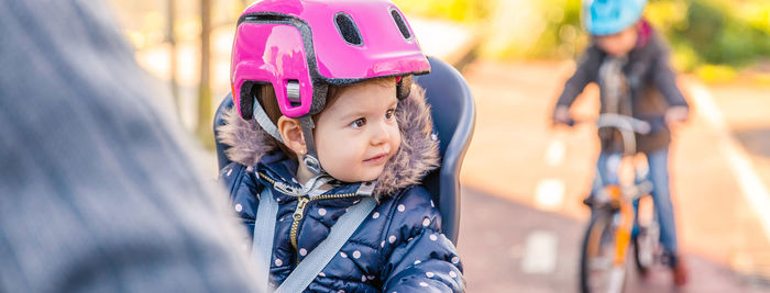 Cute baby girl looking away while riding on bicycle