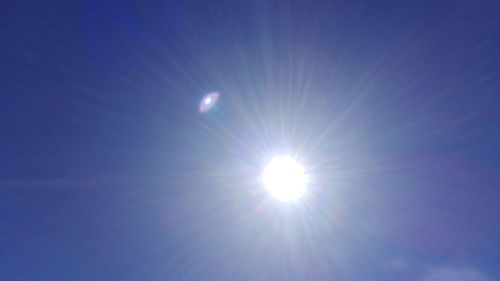 Low angle view of sun shining in blue sky