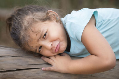 Portrait of cute girl lying on wood