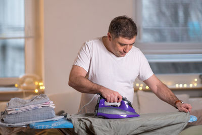 Man ironing clothes at home