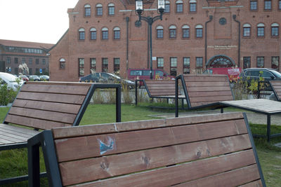 Empty park bench by buildings in city