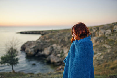 Woman looking at sea against sky during sunset