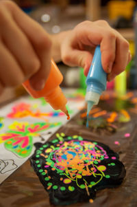 Close-up of hand holding multi colored art on table