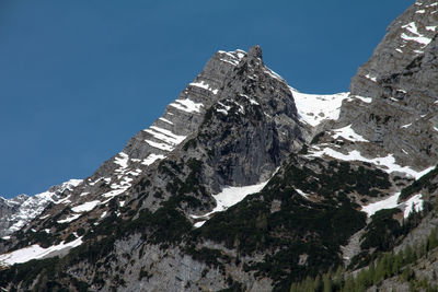 Low angle view of snowcapped mountains against clear sky