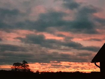 Low angle view of silhouette trees against dramatic sky