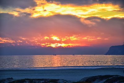 Scenic view of sea against dramatic sky during sunset