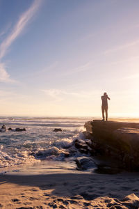 Silhouette man standing on beach against sky