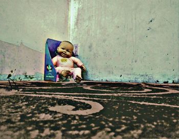 Full length of boy sitting on footpath against wall