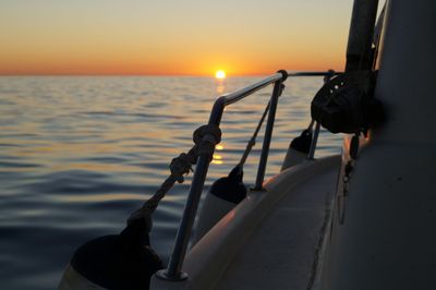 Close-up of railing against sea during sunset