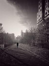 Rear view of silhouette man walking on building against sky