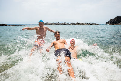 Full length of shirtless boys jumping in sea