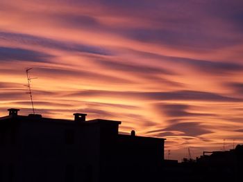 Low angle view of silhouette buildings against sunset sky