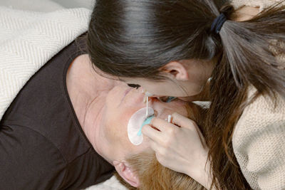 A girl cosmetologist laminates women's eyelashes.