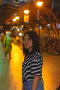 Portrait of woman standing against illuminated lights