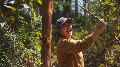 Happy young woman standing against plants