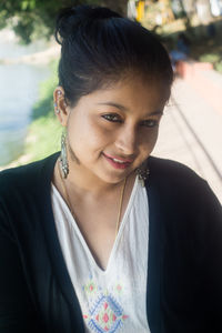 Close-up portrait of young woman smiling while standing outdoors