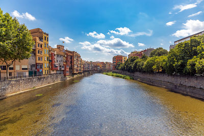 Buildings by river against sky