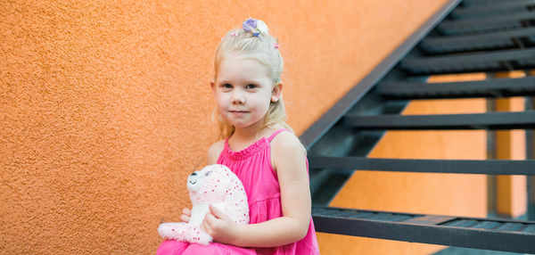 Portrait of cute girl standing against yellow wall