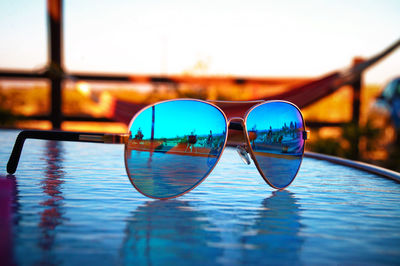 Close-up of sunglasses in swimming pool against sky