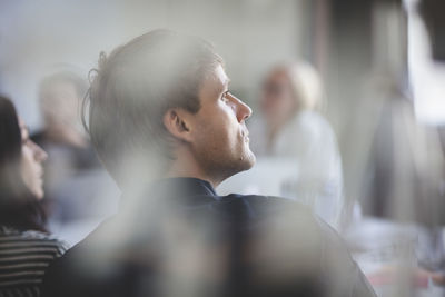 Rear view of businessman listening while sitting in board room during meeting