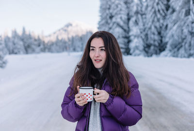 Woman drinking hot tea while on a road trip during winter.