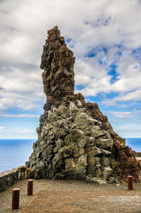 Rock formation on sea shore against sky