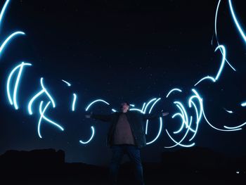 Low angle view of woman standing against sky at night