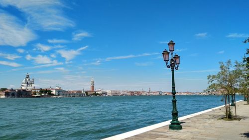 Sea by buildings against blue sky