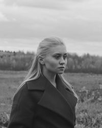 Portrait of beautiful woman standing on field against sky