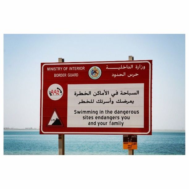 text, western script, communication, sea, transfer print, warning sign, water, guidance, information sign, sign, horizon over water, capital letter, information, auto post production filter, non-western script, red, direction, sky, beach, outdoors