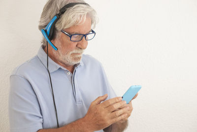 Midsection of man holding eyeglasses against wall