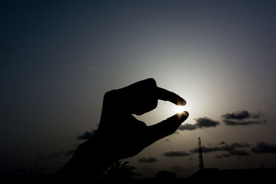 Close-up of hand holding sun against sky 