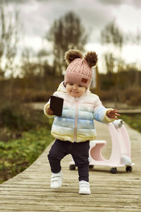 A 1 year old baby girl is with a pink motorcycle outside