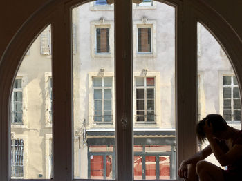 Woman sitting by window of building