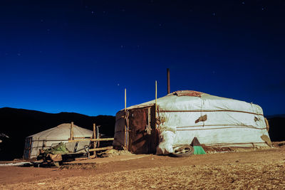 Abandoned built structure on field against clear blue sky at night