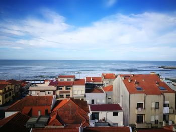 High angle view of houses by sea against cloudy sky