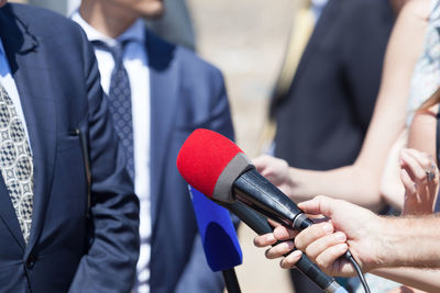 Midsection of reporters with microphones interviewing businessmen